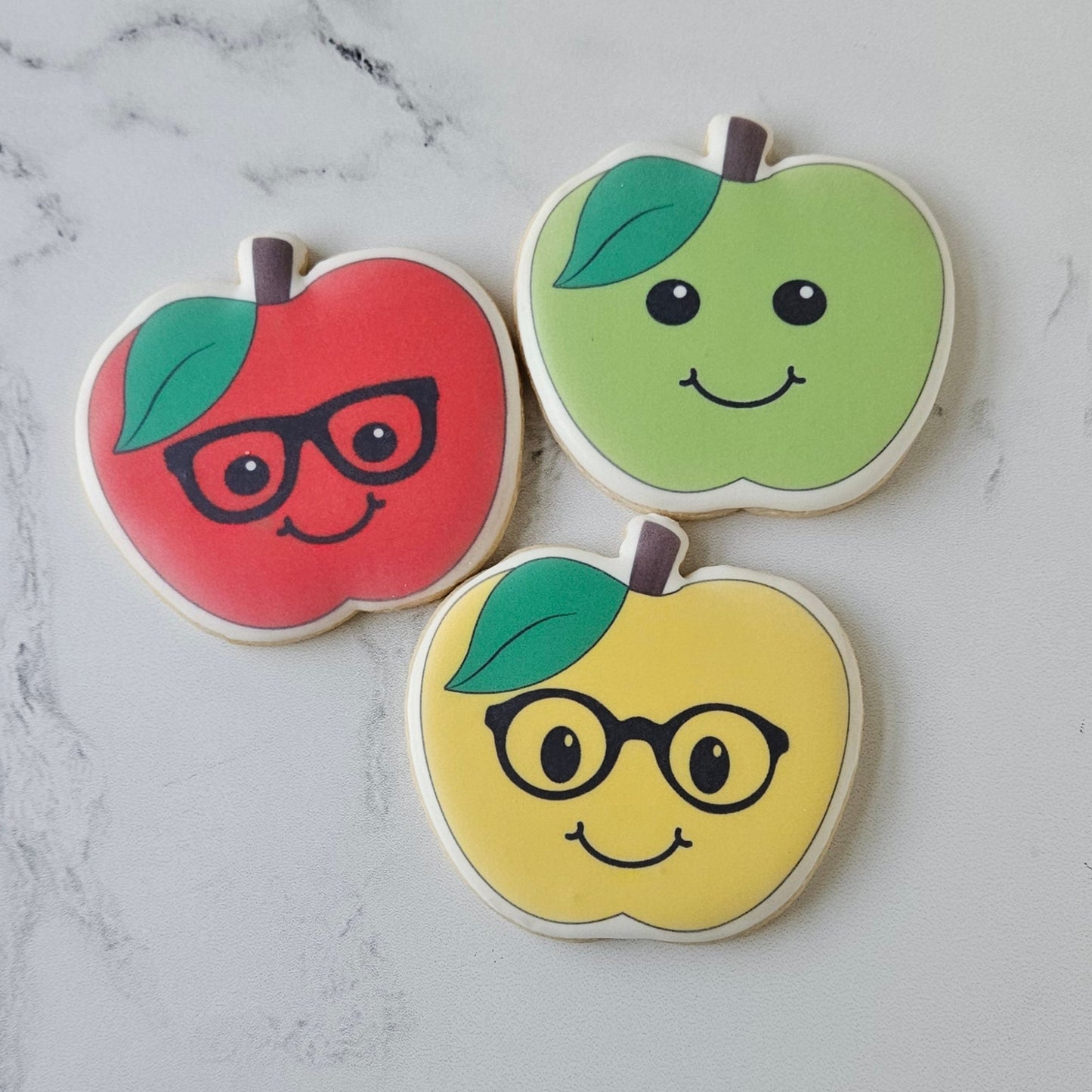 apple shaped cookies with smiling faces in red, green and yellow