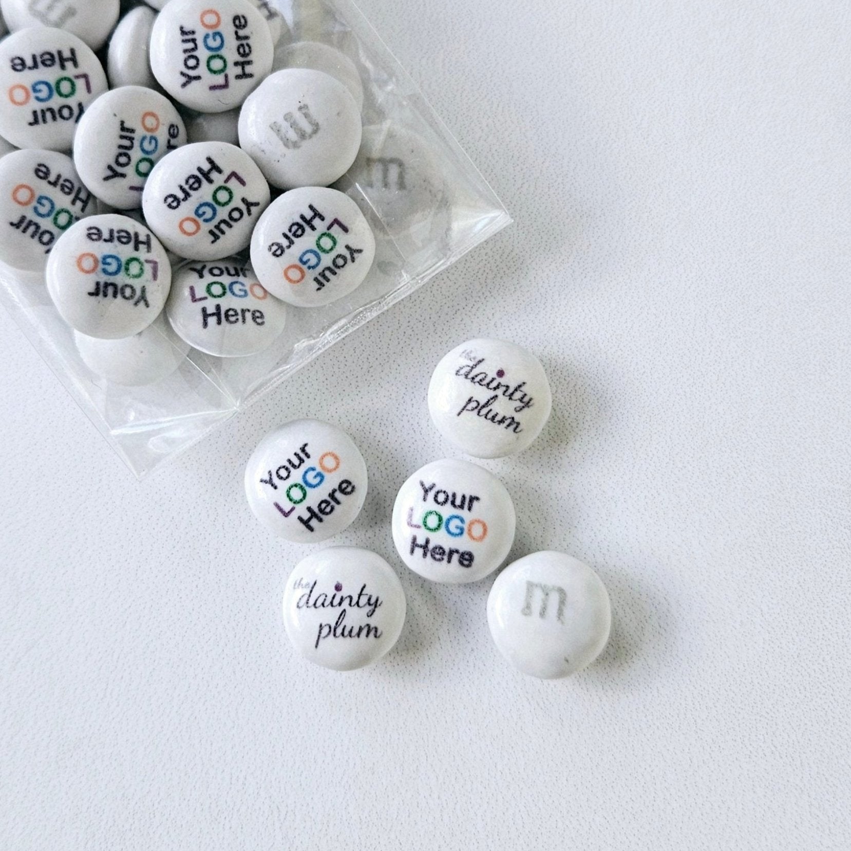 white M&Ms candy bags with custom printed text and logos in various colors.