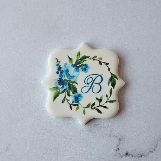plaque shape logo cookie with blue B monogram and floral wreath 